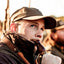 Duck hunter blowing a duck call while wearing a brown Fireside Relaxed Fit hat from DECOY, side view