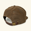 DECOY Waxed Canvas 7-panel Hat rear view showing leather strap and brass DECOY buckle on cream background