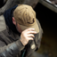 Man wearing a waxed canvas hat with a DECOY logo, adjusting it with his hand, in a blurred outdoor setting.