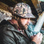 Man wearing the DECOY Frogskin Camo Jones Hat in a duck blind while lighting a pipe